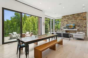 Dining room with a fireplace, recessed lighting, light wood-style floors, and view of wooded area
