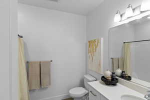 Full bathroom with toilet, a shower with curtain, visible vents, baseboards, and vanity