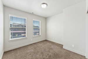 Empty room with carpet flooring, visible vents, and baseboards