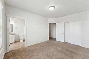 Unfurnished bedroom with a closet, baseboards, carpet flooring, visible vents, and connected bathroom