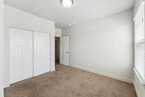 Unfurnished bedroom with carpet flooring, a closet, and baseboards