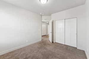Unfurnished bedroom featuring carpet floors, baseboards, visible vents, and a closet