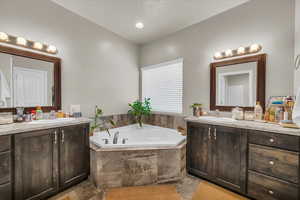 Bathroom featuring a sink, two vanities, and a bath