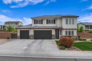 Prairie-style house featuring stone siding, an attached garage, stucco siding, fence, and concrete driveway