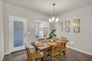 Dining area with wood finished floors, baseboards, and a notable chandelier