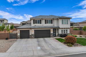 View of front facade featuring fence, stone siding, concrete driveway, a garage, and stucco siding