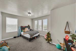 Carpeted bedroom with a textured ceiling and baseboards