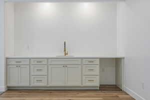 Bar featuring light wood-type flooring, baseboards, and a sink