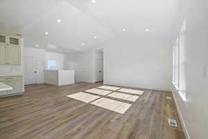 Unfurnished living room with vaulted ceiling, light wood-type flooring, visible vents, and recessed lighting