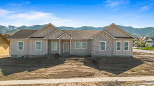 View of front facade featuring roof with shingles, stone siding, a mountain view, and board and batten siding