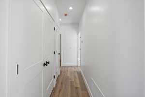 Hall featuring light wood-style floors, baseboards, and recessed lighting