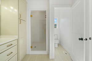 Bathroom with toilet, vanity, visible vents, a shower stall, and baseboards