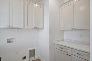 Laundry area featuring wood finished floors, electric dryer hookup, cabinet space, washer hookup, and baseboards
