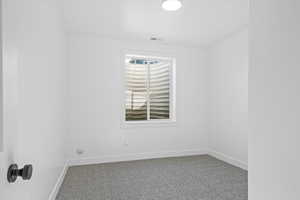 Empty room featuring carpet, visible vents, and baseboards