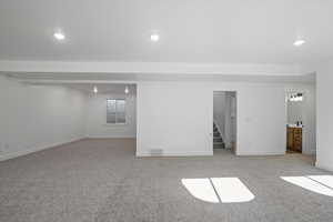 Basement featuring stairway, light colored carpet, visible vents, and recessed lighting