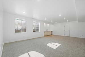 Interior space with baseboards, light carpet, recessed lighting, and a sink