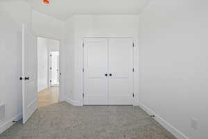 Unfurnished bedroom with carpet, a closet, and baseboards