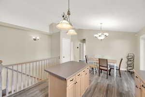 Kitchen featuring lofted ceiling, light wood finished floors, an inviting chandelier, a center island, and baseboards
