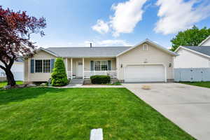 Ranch-style house with fence, a garage, concrete driveway, a porch, and a front lawn