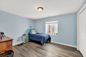 Bedroom with baseboards, a closet, visible vents, and wood finished floors