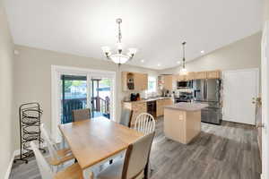Dining room with lofted ceiling, recessed lighting, a chandelier, light wood-style flooring, and baseboards