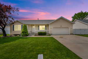 Ranch-style house with covered porch, fence, an attached garage, driveway, and a front yard
