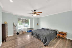 Bedroom with baseboards, ornamental molding, and wood finished floors