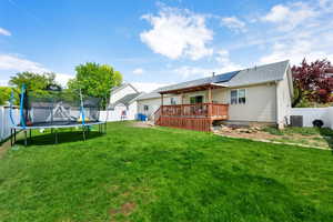 Rear view of house featuring a yard, central AC, a trampoline, a deck, and a fenced backyard