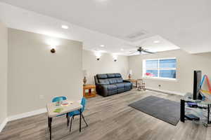Living area featuring a ceiling fan, recessed lighting, baseboards, visible vents, and wood finished floors