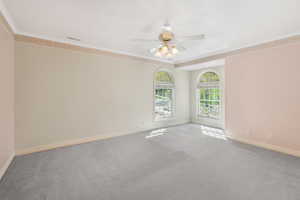 Spare room featuring baseboards, ceiling fan, visible vents, crown molding, and carpet floors