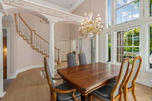 Dining room featuring an inviting chandelier, light wood-style flooring, arched walkways, and decorative columns