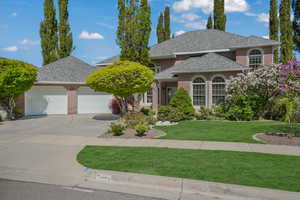 View of front of house featuring brick siding, a garage, a shingled roof, concrete driveway, and a front lawn