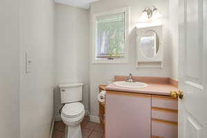 Half bath with toilet, tile patterned flooring, and vanity