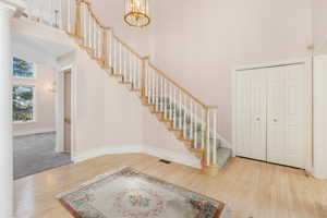 Entrance foyer featuring stairway, a chandelier, a high ceiling, and wood finished floors