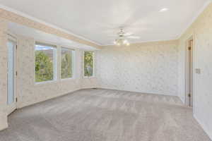 Unfurnished room with crown molding, carpet flooring, and a ceiling fan