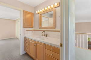 Bathroom with vanity, ornamental molding, backsplash, and baseboards