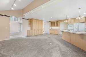 Interior space with lofted ceiling, light colored carpet, track lighting, recessed lighting, and baseboards