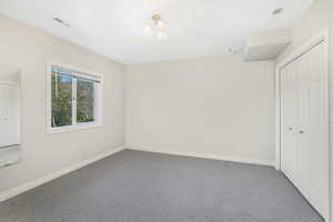 Unfurnished bedroom with carpet floors, baseboards, visible vents, and a closet