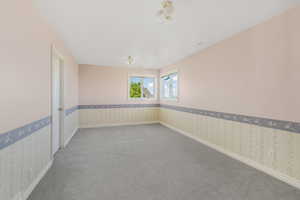 Carpeted empty room featuring baseboards and wallpapered walls