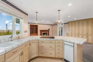 Kitchen featuring light brown cabinets, recessed lighting, a sink, a peninsula, and a fireplace