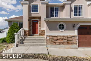View of front facade featuring stone siding, stucco siding, and an attached garage