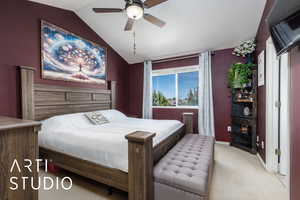 Carpeted bedroom featuring lofted ceiling, baseboards, and a ceiling fan