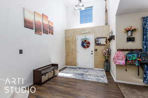 Entrance foyer with baseboards, a towering ceiling, and wood finished floors