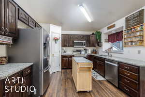 Kitchen featuring dark brown cabinets, a sink, dark wood finished floors, appliances with stainless steel finishes, and a kitchen island