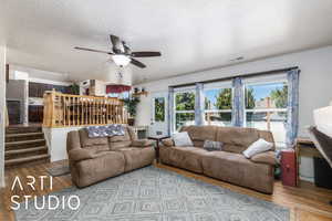 Living room featuring visible vents, ceiling fan, a textured ceiling, and wood finished floors