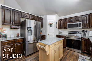 Kitchen featuring dark brown cabinetry, dark wood-style floors, light stone counters, and appliances with stainless steel finishes