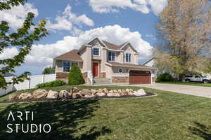 Craftsman-style house featuring fence, an attached garage, stone siding, concrete driveway, and stucco siding