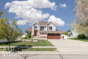 View of front facade featuring fence, an attached garage, driveway, stucco siding, and a front yard