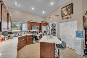 Kitchen featuring stainless steel appliances, tasteful backsplash, a breakfast bar, high vaulted ceiling, and a kitchen island
