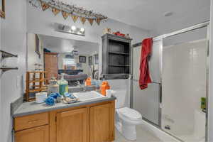 Bathroom featuring a ceiling fan, vanity, toilet, and a shower stall